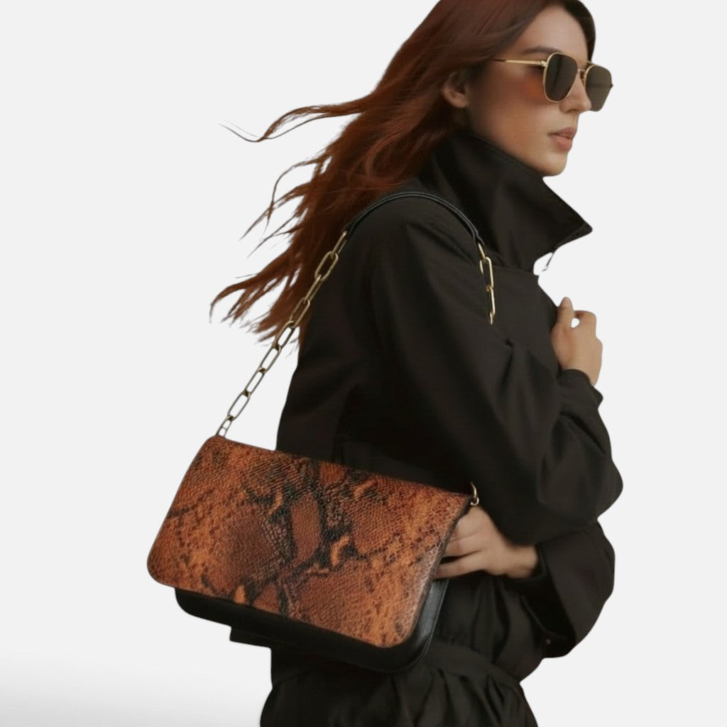 Rabat La Stella pour sac Baby en cuir de vachette embossé effet python aux nuances cuivrées et noires porté à l'épaule