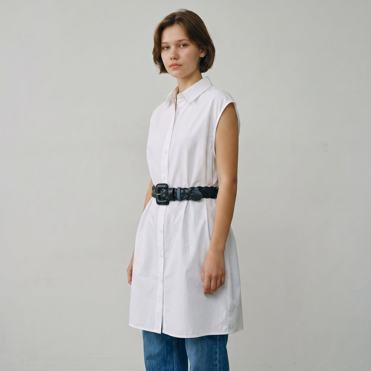 Femme portant une ceinture tressée en cuir noir La Stella avec une boucle géométrique sur une robe chemise blanche