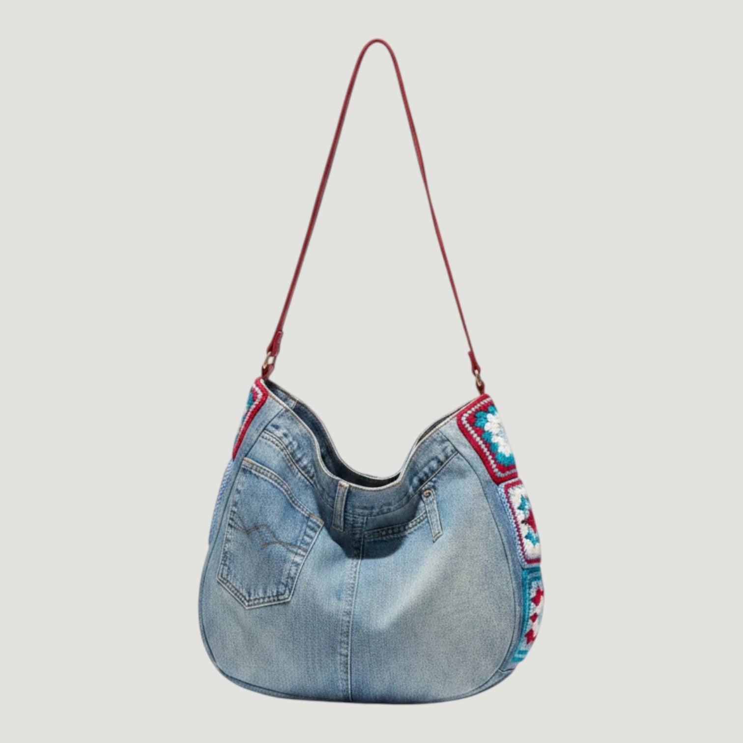 La Stella sac bandoulière en jean recyclé bleu clair avec détails au crochet coloré et anse en cuir rouge.